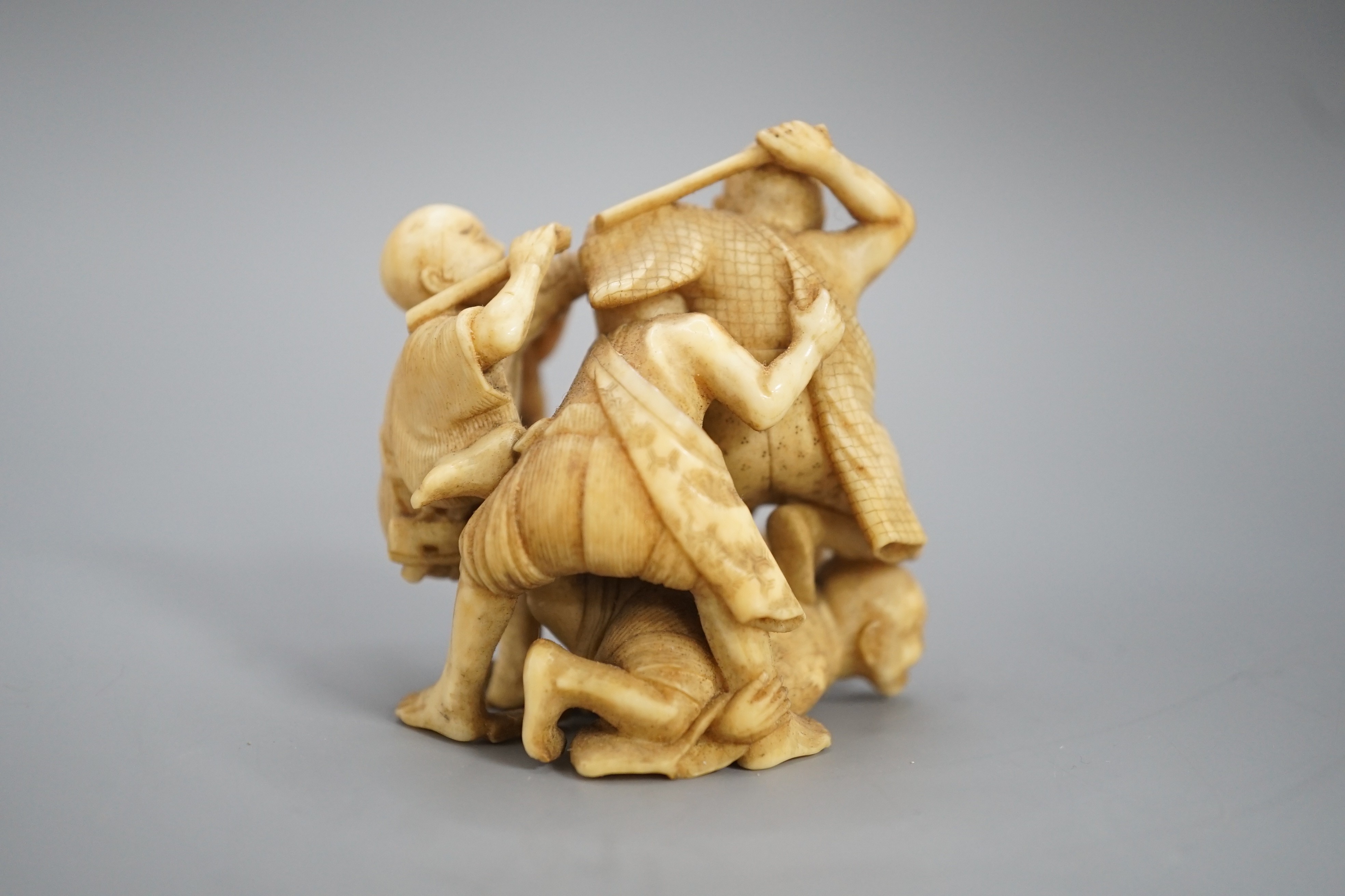 A Japanese ivory group of four men fighting, signed, Meiji period, 5.5cm